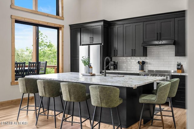 2634 Whipoorwill Hill Way, Sevierville, TN 37862 - kitchen with under cabinet range hood, freestanding refrigerator, dark cabinets, tasteful backsplash, and light stone countertops