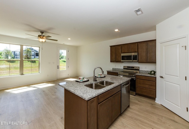1334 Mountain Quail Cir, Maryville, TN 37801 - kitchen featuring appliances with stainless steel finishes, light wood-type flooring, light stone countertops, a ceiling fan, and a kitchen island with sink