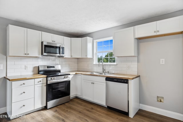 165 Kenzie Ln, Lafollette, TN 37766 - kitchen featuring appliances with stainless steel finishes, wooden counters, white cabinets, wood finished floors, and tasteful backsplash