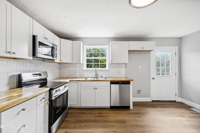 165 Kenzie Ln, Lafollette, TN 37766 - kitchen featuring butcher block countertops, appliances with stainless steel finishes, dark wood finished floors, white cabinets, and decorative backsplash