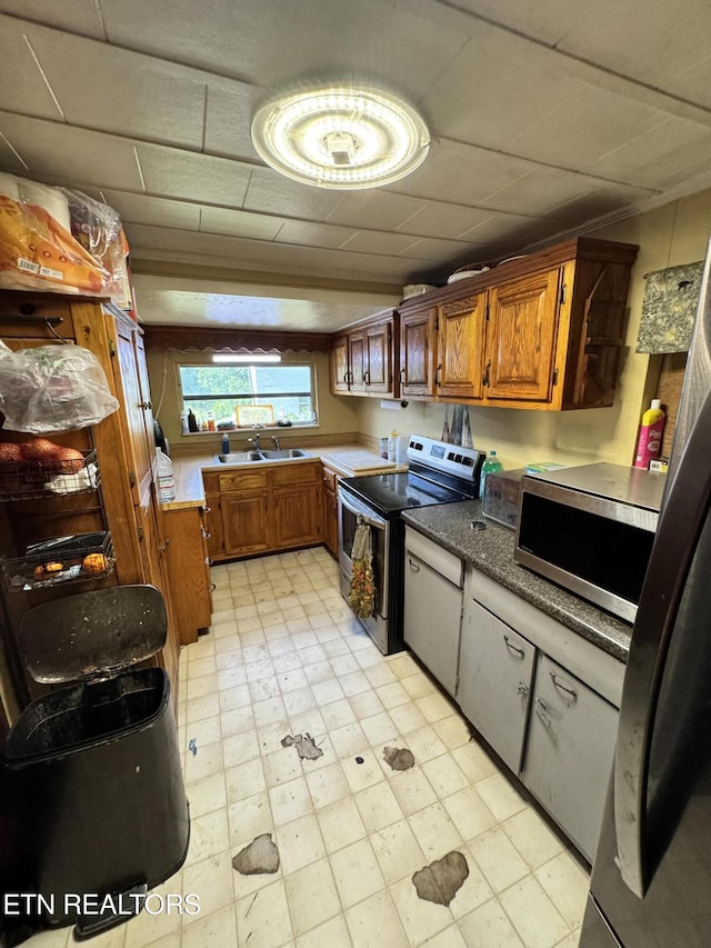 2395 Howard Rd, Bybee, TN 37713 - kitchen with appliances with stainless steel finishes, brown cabinets, a drop ceiling, light flooring, and a sink