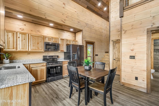 2251 Fox Berry Way, Sevierville, TN 37876 - kitchen with stainless steel appliances, light brown cabinets, wood walls, high vaulted ceiling, and wood finished floors