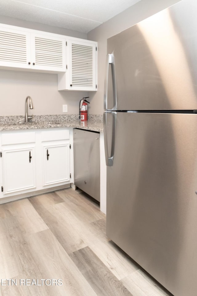 3815 E E Pkwy Apt 13, Gatlinburg, TN 37738 - kitchen featuring stainless steel appliances, light wood finished floors, white cabinetry, and light stone countertops
