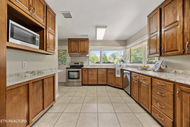 386 E Dr, Oak Ridge, TN 37830 - kitchen with appliances with stainless steel finishes, under cabinet range hood, brown cabinets, and light tile patterned floors