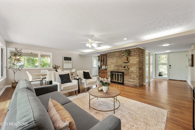 386 E Dr, Oak Ridge, TN 37830 - living room with light wood-style flooring, ceiling fan, a stone fireplace, healthy amount of natural light, and a textured ceiling