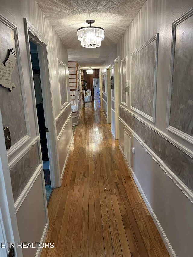 242 Adams Ln, Jellico, TN 37762 - hallway with wood-type flooring, a chandelier, a decorative wall, a textured ceiling, and washer / clothes dryer