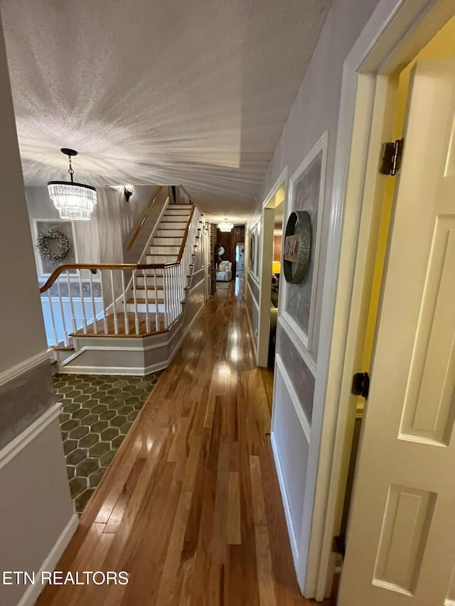 242 Adams Ln, Jellico, TN 37762 - hall featuring stairs, wood finished floors, a chandelier, and a textured ceiling