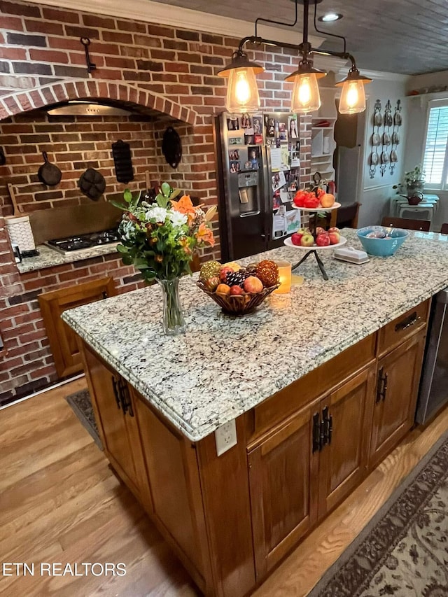 242 Adams Ln, Jellico, TN 37762 - kitchen featuring brick wall, stainless steel fridge with ice dispenser, a center island, light stone countertops, and gas stovetop
