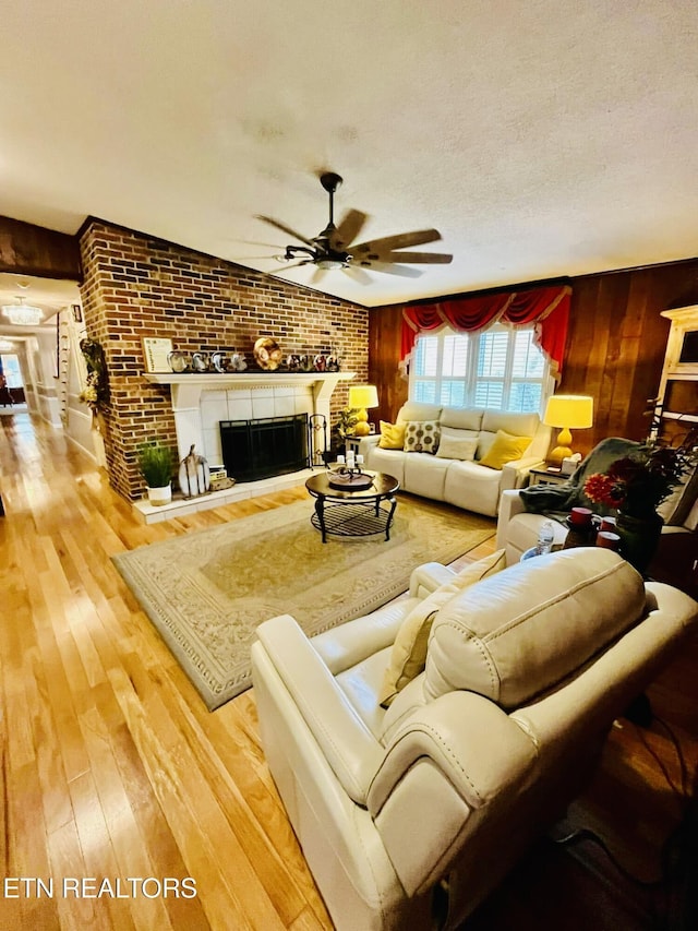242 Adams Ln, Jellico, TN 37762 - living room featuring a ceiling fan, wood-type flooring, a fireplace, brick wall, and wooden walls