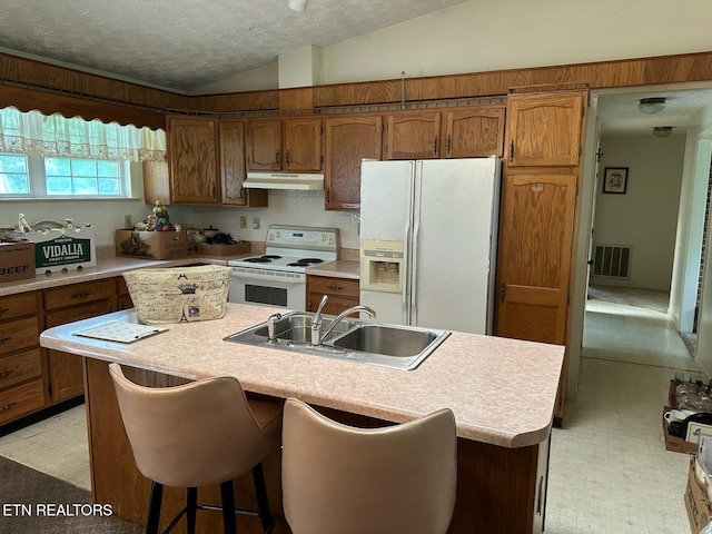 165 Bud Hatmaker Ln, Lafollette, TN 37766 - kitchen with white appliances, under cabinet range hood, vaulted ceiling, light countertops, and brown cabinetry