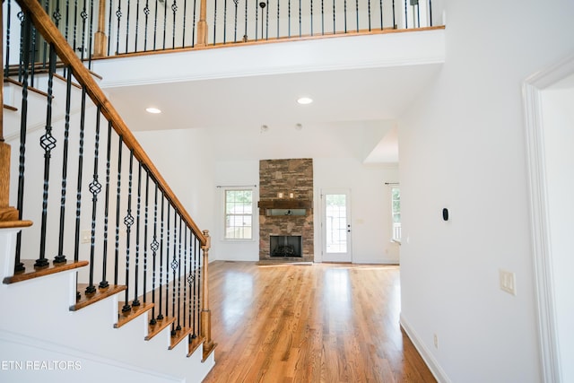 7481 Nightfall Cir, Ooltewah, TN 37363 - unfurnished living room featuring wood finished floors, stairway, a fireplace, a towering ceiling, and recessed lighting
