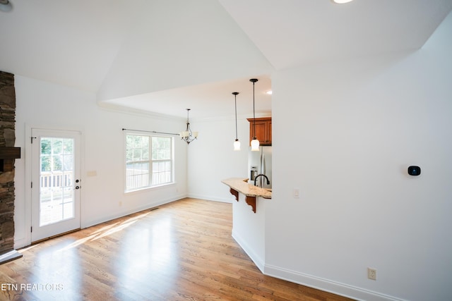7481 Nightfall Cir, Ooltewah, TN 37363 - unfurnished living room featuring a fireplace, a chandelier, light wood-style floors, and lofted ceiling
