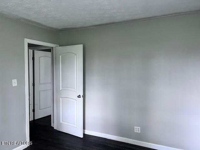 7832 Brickyard Rd, Powell, TN 37849 - unfurnished bedroom featuring baseboards, dark wood-type flooring, and a textured ceiling