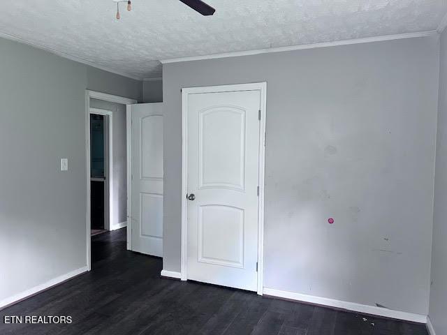 7832 Brickyard Rd, Powell, TN 37849 - unfurnished bedroom featuring dark wood-style flooring, baseboards, a textured ceiling, crown molding, and ceiling fan