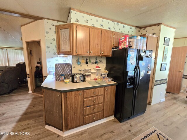 417 Ely Town Rd, Dryden, VA 24243 - kitchen with black fridge, light wood-style floors, wallpapered walls, brown cabinetry, and a textured ceiling