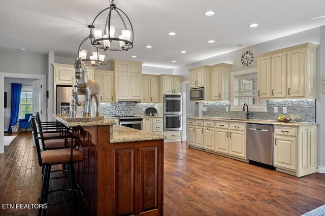 3292 Moss Arcott Rd, Celina, TN 38551 - kitchen with appliances with stainless steel finishes, cream cabinetry, a sink, dark wood finished floors, and light stone counters