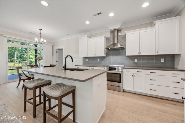 1007 Wigmore Way, Knoxville, TN 37932 - kitchen featuring stainless steel electric stove, wall chimney range hood, a kitchen breakfast bar, an island with sink, and a chandelier