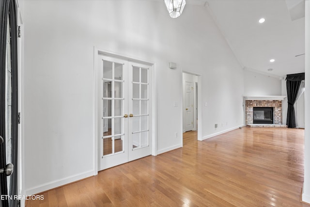 140 Chuniloti Way, Loudon, TN 37774 - unfurnished living room with french doors, a brick fireplace, ornamental molding, lofted ceiling, and light wood-style flooring