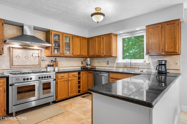 1312 Zachary Taylor Rd, Knoxville, TN 37922 - kitchen with stainless steel appliances, wall chimney exhaust hood, a peninsula, brown cabinetry, and decorative backsplash