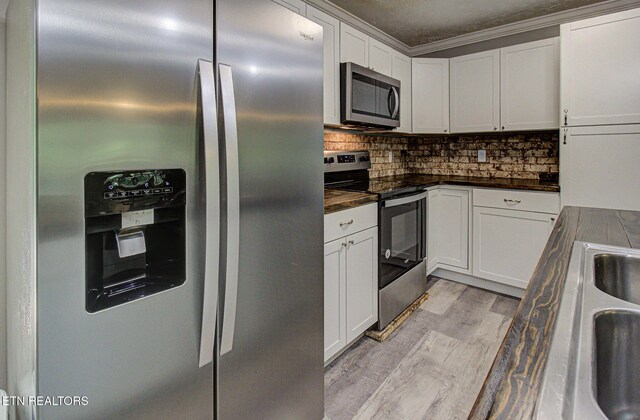 775 Middle Creek Rd, Cosby, TN 37722 - kitchen featuring stainless steel appliances, dark countertops, light wood-type flooring, backsplash, and white cabinets