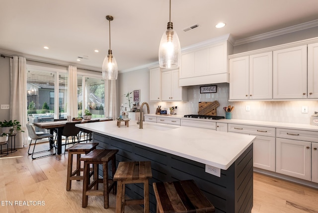 11914 Sandy Run Rd, Knoxville, TN 37934 - kitchen with gas stovetop, light countertops, a breakfast bar, a center island with sink, and crown molding