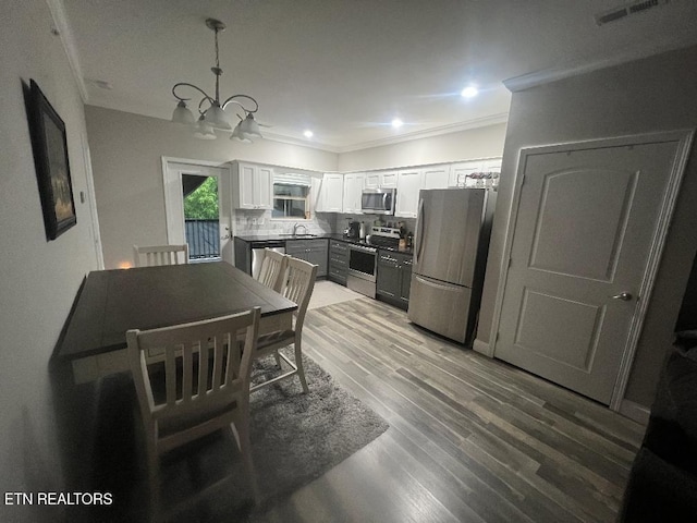 326 Shooting Star Loop Unit 201, Townsend, TN 37882 - kitchen with appliances with stainless steel finishes, a chandelier, decorative backsplash, white cabinets, and crown molding