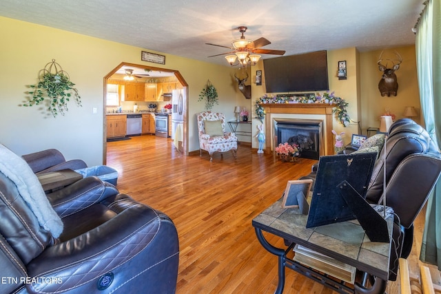 361 River Dr, Dunlap, TN 37327 - living area with a ceiling fan, a fireplace, light wood-type flooring, a textured ceiling, and arched walkways