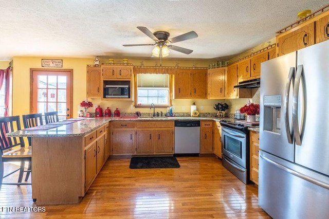361 River Dr, Dunlap, TN 37327 - kitchen with stainless steel appliances, under cabinet range hood, a peninsula, a textured ceiling, and a breakfast bar area
