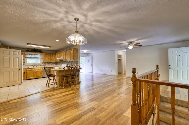 609 Lane Hollow Rd, Sevierville, TN 37876 - kitchen with a textured ceiling, plenty of natural light, light wood-style floors, a breakfast bar area, and under cabinet range hood