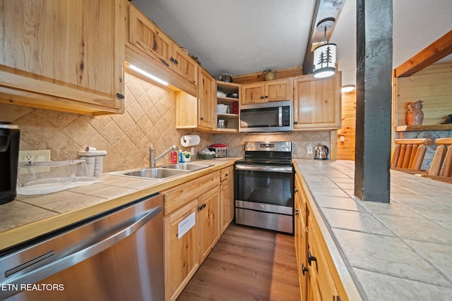 1516 Zurich Rd, Gatlinburg, TN 37738 - kitchen with appliances with stainless steel finishes, tile counters, decorative backsplash, wood finished floors, and a textured ceiling