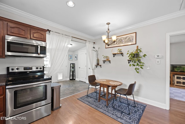 1132 Connecticut Ave, Knoxville, TN 37921 - kitchen featuring appliances with stainless steel finishes, crown molding, a chandelier, dark countertops, and wood finished floors
