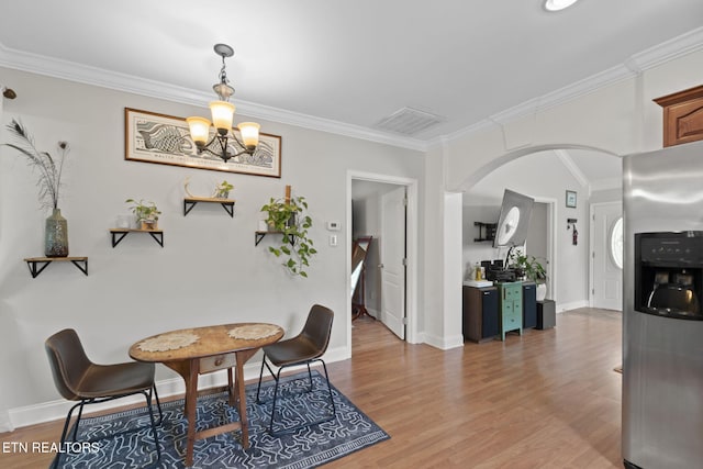 1132 Connecticut Ave, Knoxville, TN 37921 - dining area featuring arched walkways, a chandelier, ornamental molding, and light wood-style flooring