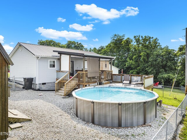 155 Kay Springs Cir, Jacksboro, TN 37757 - back of house with a wooden deck, a fenced backyard, an outdoor pool, and a metal roof