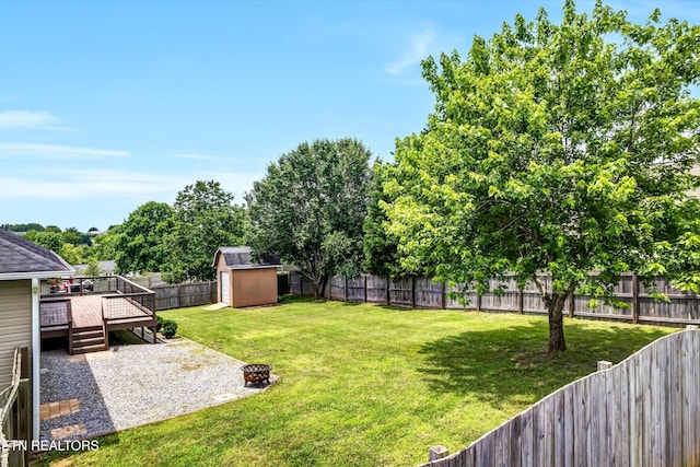 235 Jessie Ln, Lenoir City, TN 37772 - fenced backyard with a deck, a fire pit, and a storage unit