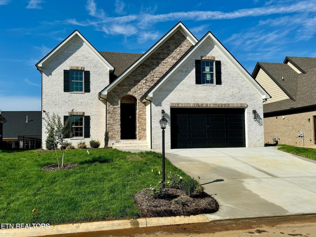 2135 Lantern Park Ln, Knoxville, TN 37932 - french country style house featuring driveway, a front yard, stone siding, and an attached garage
