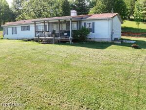 2517 Shields Ferry Rd, Morristown, TN 37814 - back of property featuring a lawn, a wooden deck, a chimney, and view of scattered trees