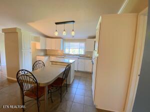 2517 Shields Ferry Rd, Morristown, TN 37814 - kitchen featuring white cabinets, dark tile patterned floors, light countertops, and a kitchen breakfast bar