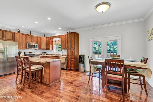 1721 N Parkridge Dr, Knoxville, TN 37924 - kitchen featuring appliances with stainless steel finishes, ornamental molding, a breakfast bar area, a kitchen island, and light wood-style floors