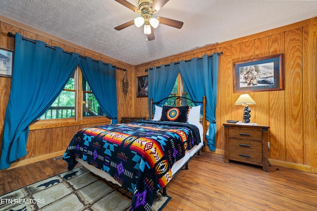 719 Kings Hills Blvd, Pigeon Forge, TN 37863 - bedroom featuring a textured ceiling, wood finished floors, wood walls, and ceiling fan