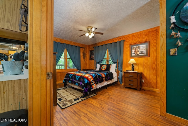 719 Kings Hills Blvd, Pigeon Forge, TN 37863 - bedroom featuring wood finished floors, wooden walls, a textured ceiling, and a ceiling fan