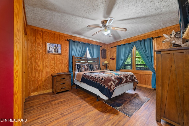 719 Kings Hills Blvd, Pigeon Forge, TN 37863 - bedroom featuring wood finished floors, wooden walls, a textured ceiling, and a ceiling fan