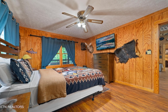 719 Kings Hills Blvd, Pigeon Forge, TN 37863 - bedroom with a textured ceiling, wood finished floors, wood walls, and ceiling fan