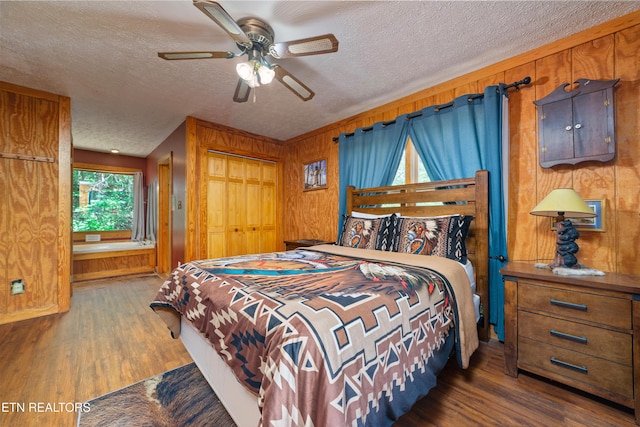 719 Kings Hills Blvd, Pigeon Forge, TN 37863 - bedroom with wood walls, wood finished floors, a textured ceiling, ceiling fan, and a closet