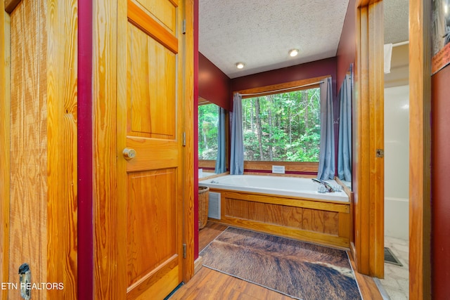 719 Kings Hills Blvd, Pigeon Forge, TN 37863 - bathroom with a textured ceiling, a bath, wood finished floors, and lofted ceiling