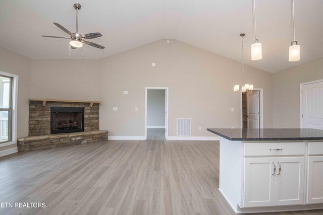 2609 Mountain Blvd, Sevierville, TN 37876 - unfurnished living room with vaulted ceiling, a ceiling fan, a fireplace, light wood-style floors, and a chandelier