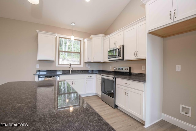 2609 Mountain Blvd, Sevierville, TN 37876 - kitchen featuring stainless steel appliances, light wood finished floors, white cabinetry, vaulted ceiling, and dark stone counters
