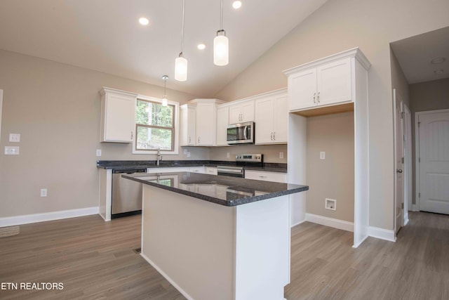 2609 Mountain Blvd, Sevierville, TN 37876 - kitchen with appliances with stainless steel finishes, white cabinetry, light wood finished floors, a center island, and vaulted ceiling