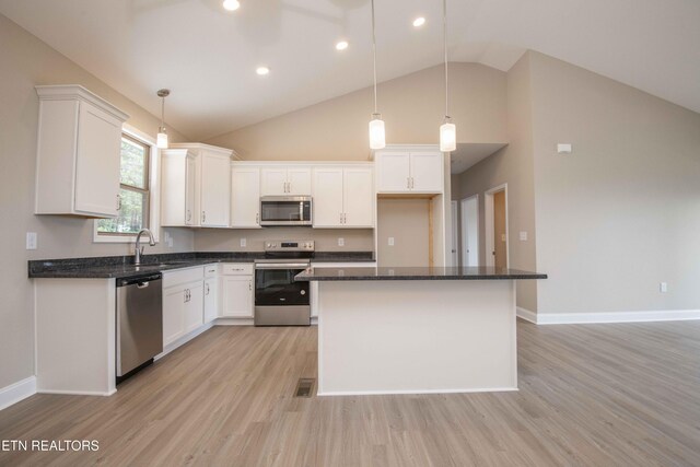 2609 Mountain Blvd, Sevierville, TN 37876 - kitchen with appliances with stainless steel finishes, light wood finished floors, white cabinetry, high vaulted ceiling, and a kitchen island