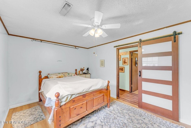 225 Spring St, Spring City, TN 37381 - bedroom featuring ornamental molding, a textured ceiling, wood finished floors, a barn door, and a ceiling fan