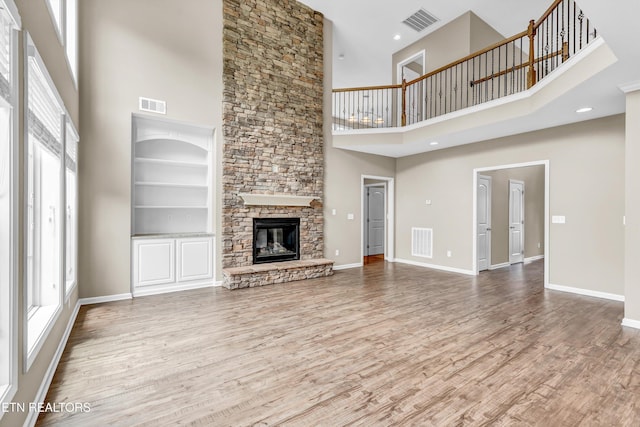 2017 Gusty Wind Ln, Knoxville, TN 37932 - unfurnished living room featuring a towering ceiling, a stone fireplace, wood finished floors, and built in features